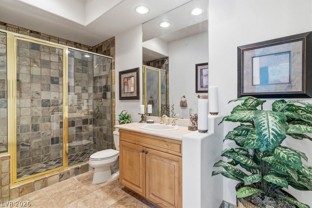 1632 Marbella Ridge Court, Las Vegas, NV 89117 A glass-enclosed walk-in tile shower anchors this bathroom beside a wood vanity.