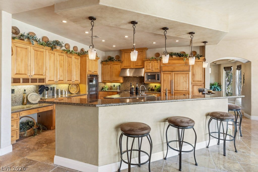 1632 Marbella Ridge Court, Las Vegas, NV 89117 Rich wood cabinetry and polished granite counters anchor this spacious, tile-floored culinary space.