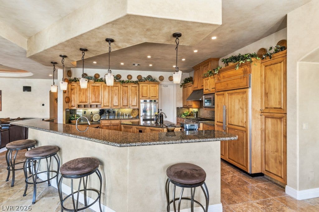 1632 Marbella Ridge Court, Las Vegas, NV 89117 Richly grained cabinetry and polished stone countertops define this expansive kitchen workspace.