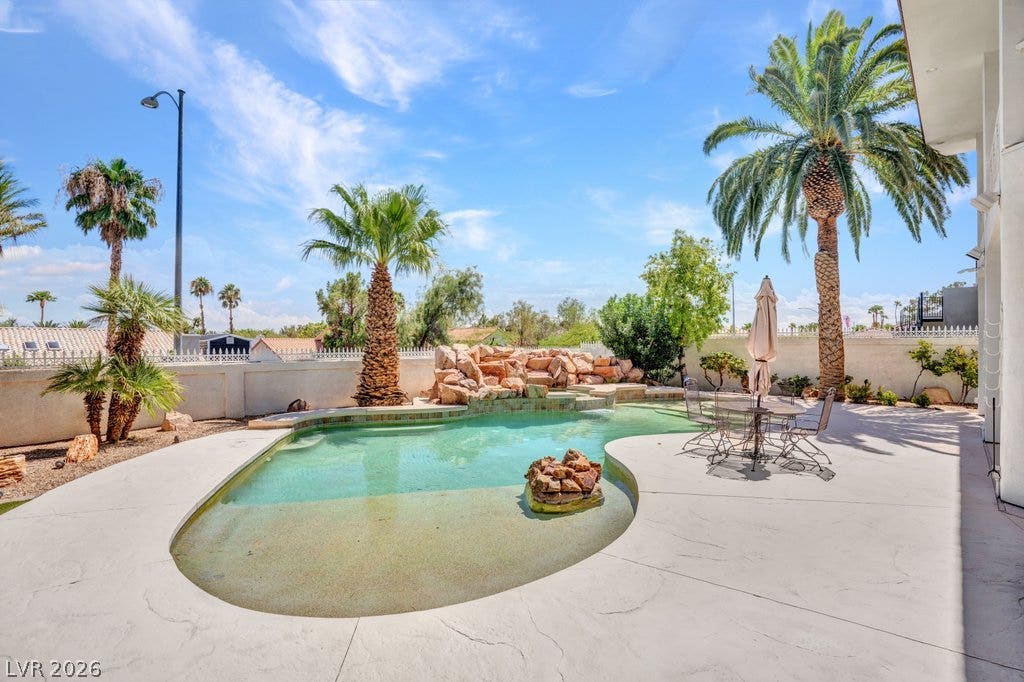 1632 Marbella Ridge Court, Las Vegas, NV 89117 A sparkling resort-style pool is bordered by concrete decking and towering palm trees.