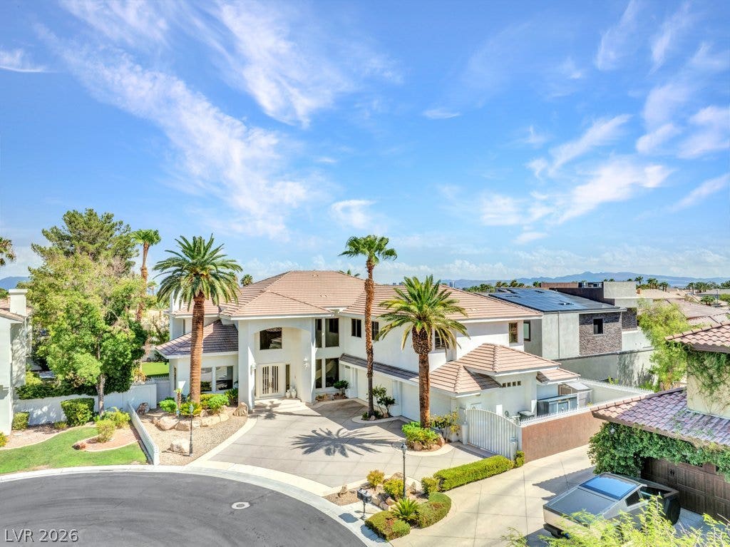1632 Marbella Ridge Court, Las Vegas, NV 89117 Palm trees frame the arched entryway and tiled rooflines of this modern two-story estate.