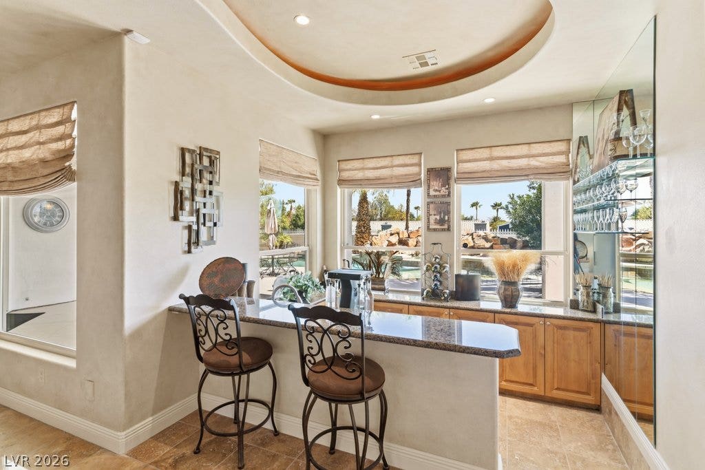 1632 Marbella Ridge Court, Las Vegas, NV 89117 An elegant wet bar features custom granite countertops, tile flooring, and a unique recessed ceiling detail.