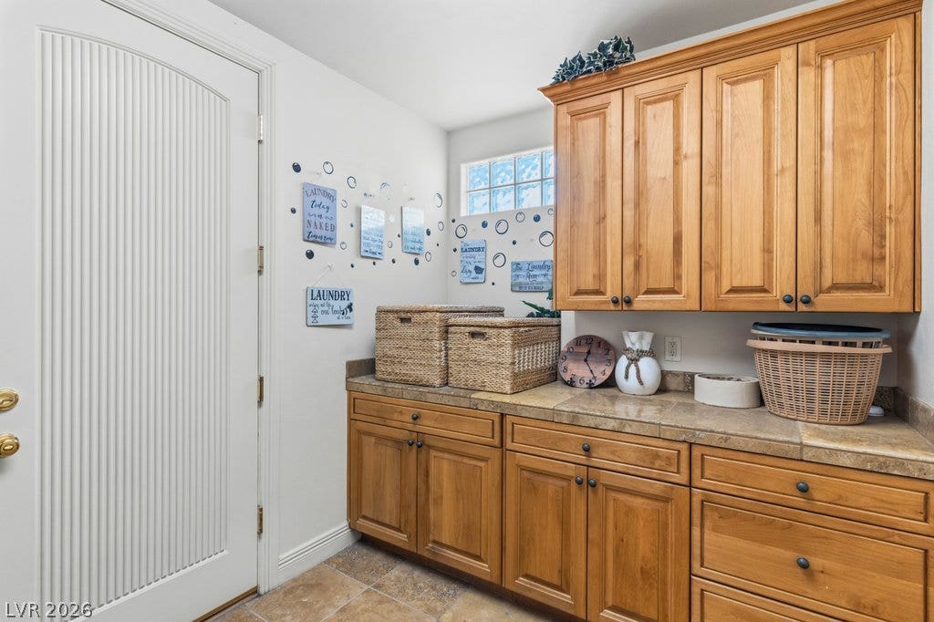 1632 Marbella Ridge Court, Las Vegas, NV 89117 Ample built-in cabinetry and durable tile flooring highlight this functional utility space.