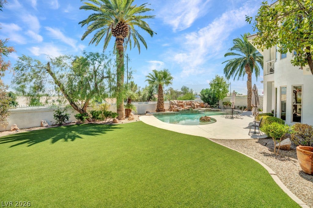 1632 Marbella Ridge Court, Las Vegas, NV 89117 Lush green lawn pairs beautifully with a sparkling backyard pool and towering palm trees.
