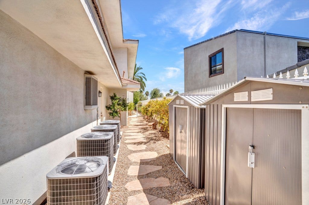 1632 Marbella Ridge Court, Las Vegas, NV 89117 A stone pathway leads through the side yard past stucco walls and storage structures.