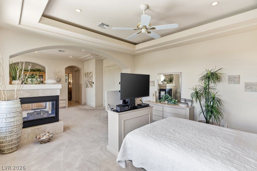 1632 Marbella Ridge Court, Las Vegas, NV 89117 An elegant tray ceiling and cozy fireplace anchor this spacious primary bedroom suite.