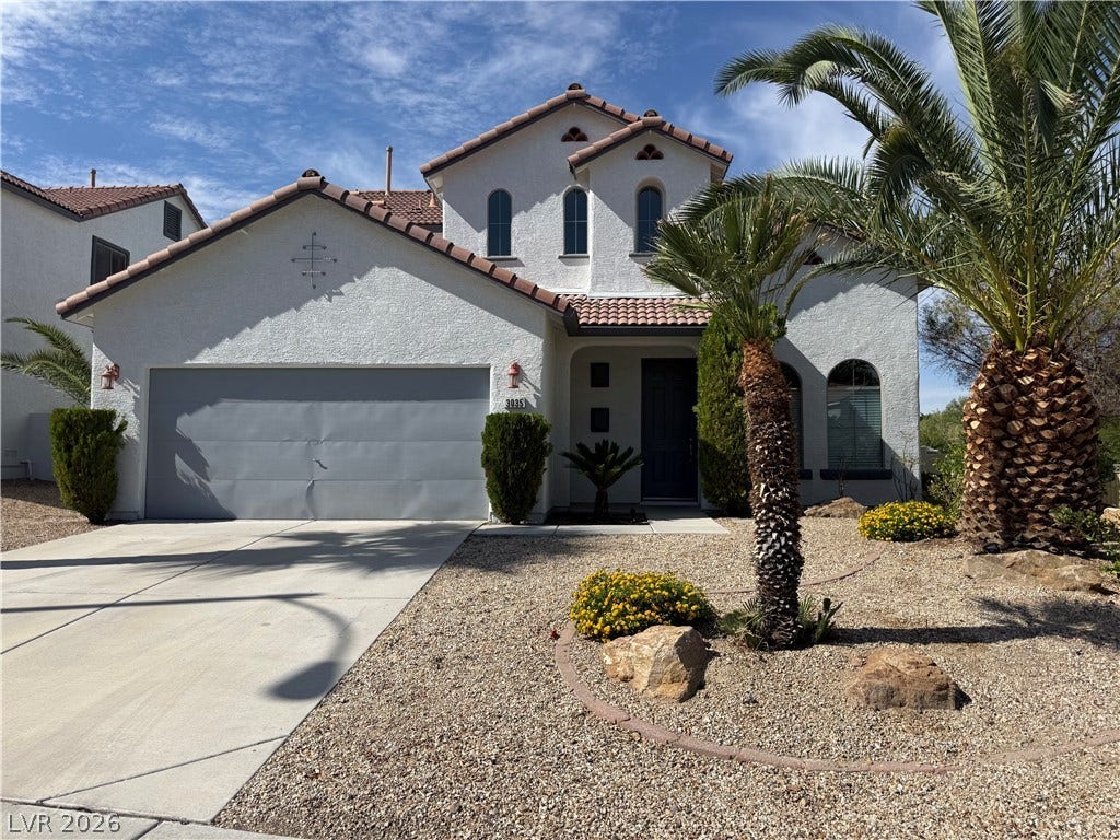 Spanish tile rooflines and stucco finishes define this desert-landscaped home with arched windows.