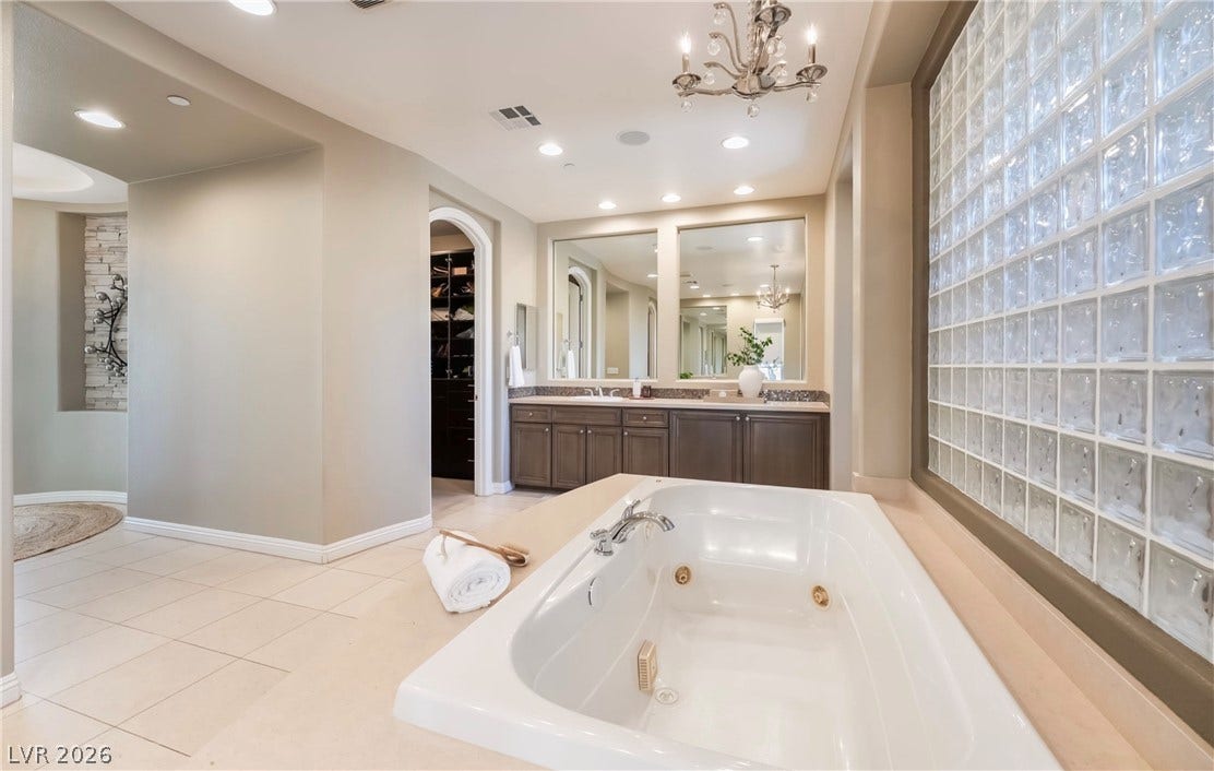 1343 Quiet River Avenue, Henderson, NV 89012 An integrated soaking tub, recessed lighting, and a glass block window accent this bathroom space.