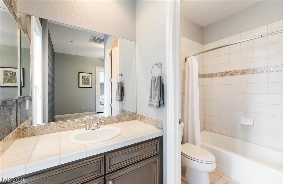 1343 Quiet River Avenue, Henderson, NV 89012 Tile countertops and a tub shower setup define this functional bathroom space.
