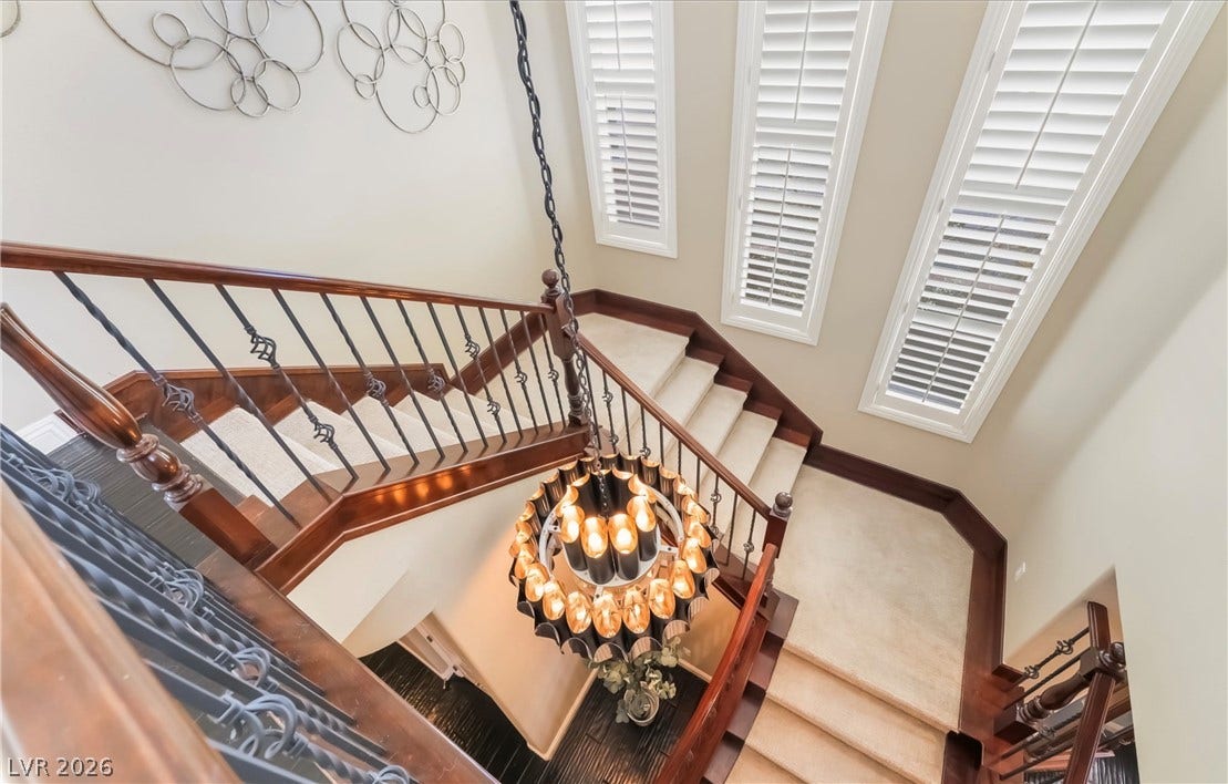 1343 Quiet River Avenue, Henderson, NV 89012 An elegant multi-level staircase features classic wooden handrails and towering windows with plantation shutters.
