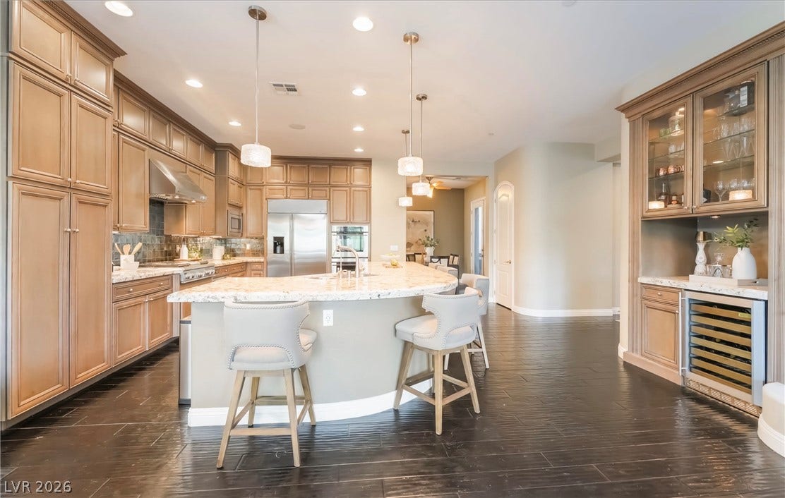 1343 Quiet River Avenue, Henderson, NV 89012 Rich wood cabinetry and a curved granite island anchor this expansive chef's kitchen.