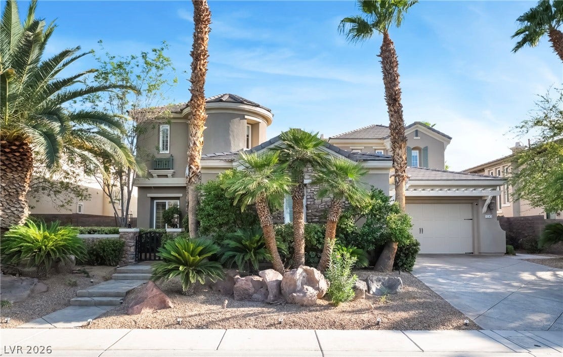 1343 Quiet River Avenue, Henderson, NV 89012 Lush palm trees frame this elegant multi-level home featuring stone accents and a private driveway.