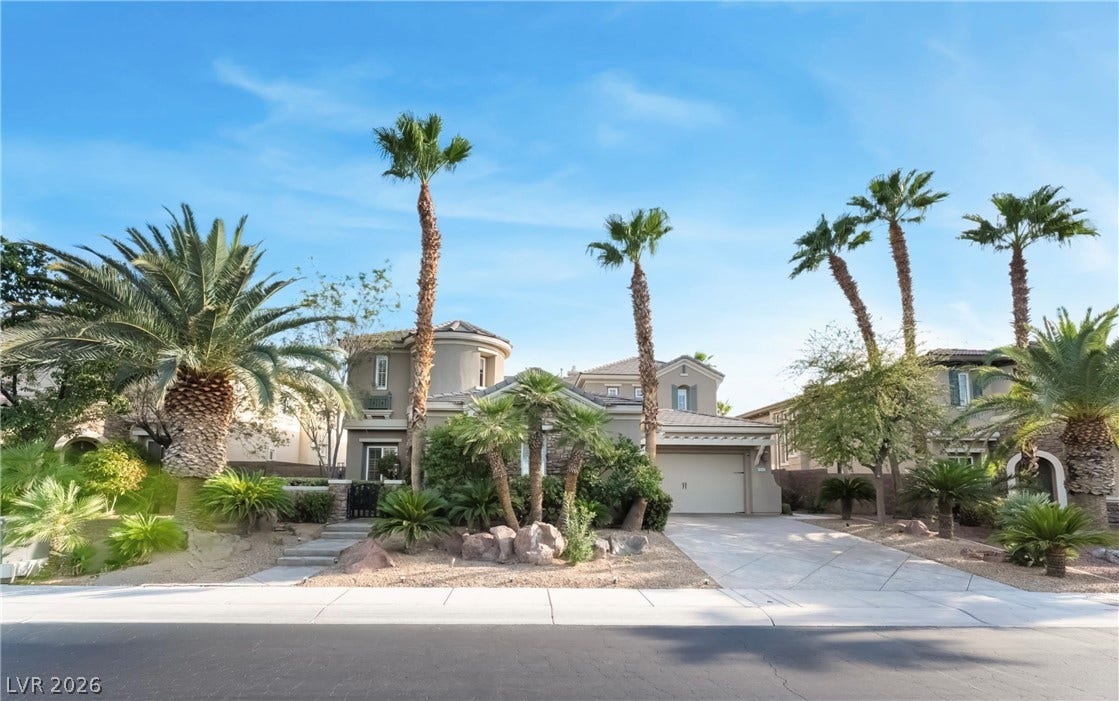 1343 Quiet River Avenue, Henderson, NV 89012 Palm trees frame the stucco exterior and concrete driveway of this multi-level desert residence.