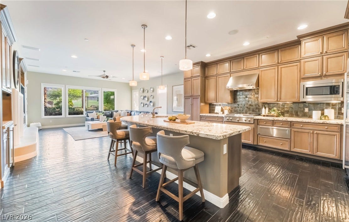 1343 Quiet River Avenue, Henderson, NV 89012 Gleaming dark flooring flows seamlessly from the open kitchen into the adjacent living space.
