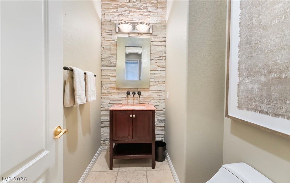1343 Quiet River Avenue, Henderson, NV 89012 Stacked stone creates a textured accent wall behind a modern single vanity on tiled flooring.