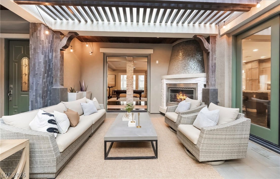 1343 Quiet River Avenue, Henderson, NV 89012 An inviting covered patio offers a cozy stone fireplace under a classic wood pergola.