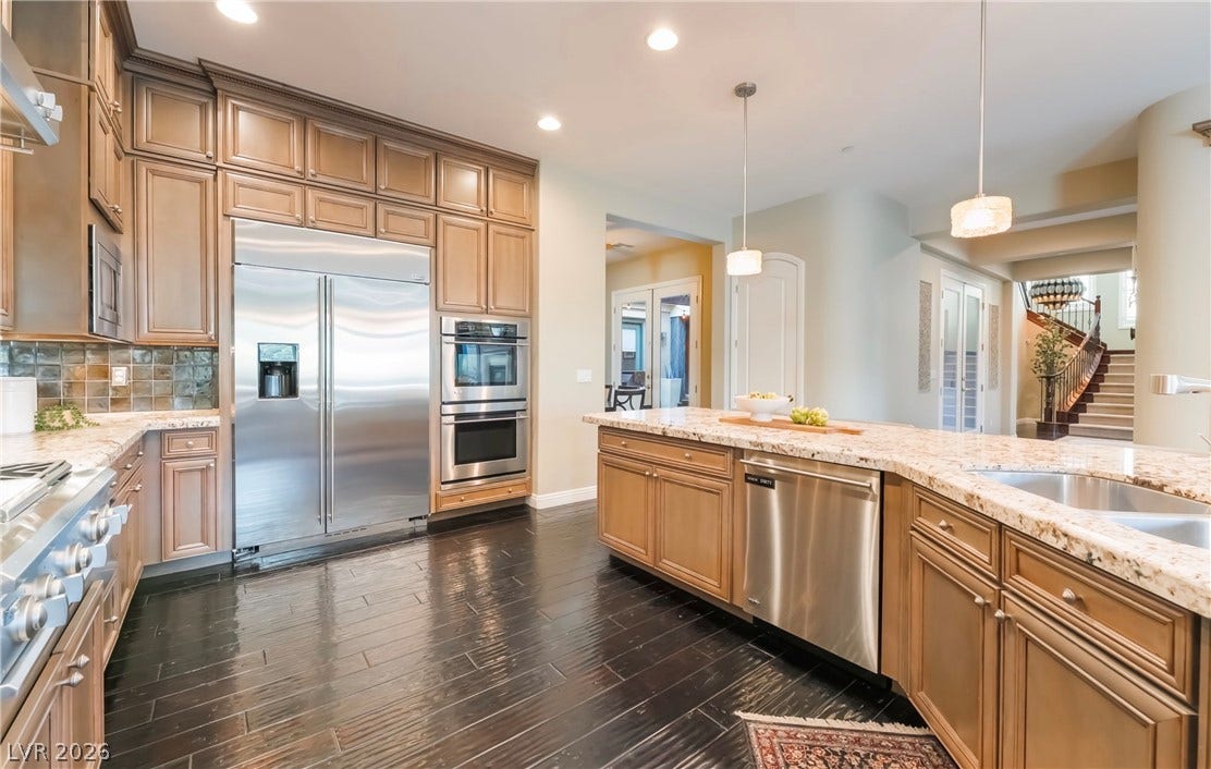 1343 Quiet River Avenue, Henderson, NV 89012 Rich hardwood floors contrast with granite countertops and custom cabinetry in this open kitchen.