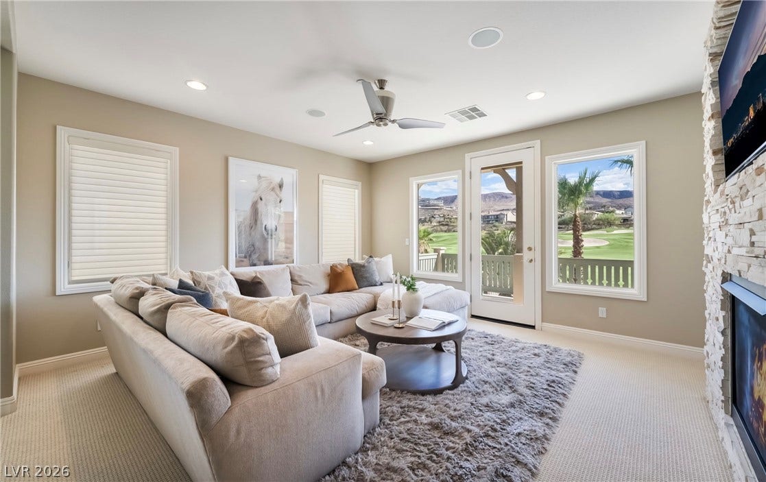 1343 Quiet River Avenue, Henderson, NV 89012 A stone fireplace anchors this living space, offering scenic golf course views through large windows.