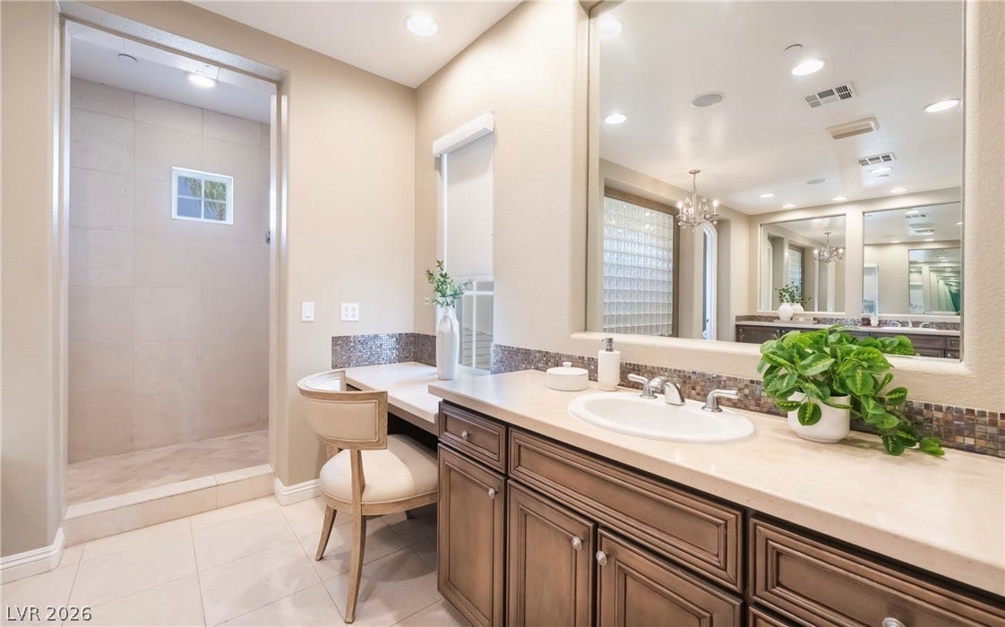 1343 Quiet River Avenue, Henderson, NV 89012 Stone counters and custom cabinetry elevate this modern bathroom layout.