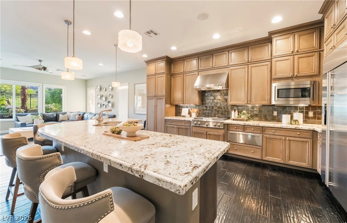 1343 Quiet River Avenue, Henderson, NV 89012 An expansive kitchen features custom cabinetry, premium stone countertops, and dark hardwood flooring.