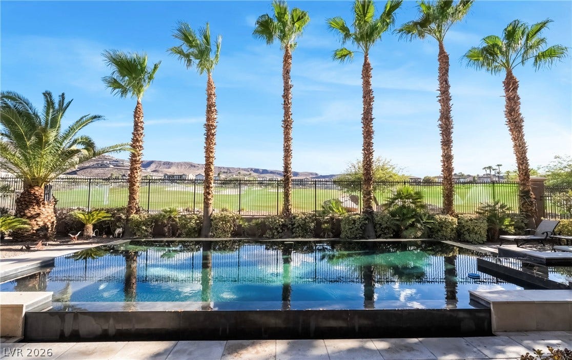 1343 Quiet River Avenue, Henderson, NV 89012 Towering palm trees frame an inviting pool overlooking a scenic golf course and distant hills.
