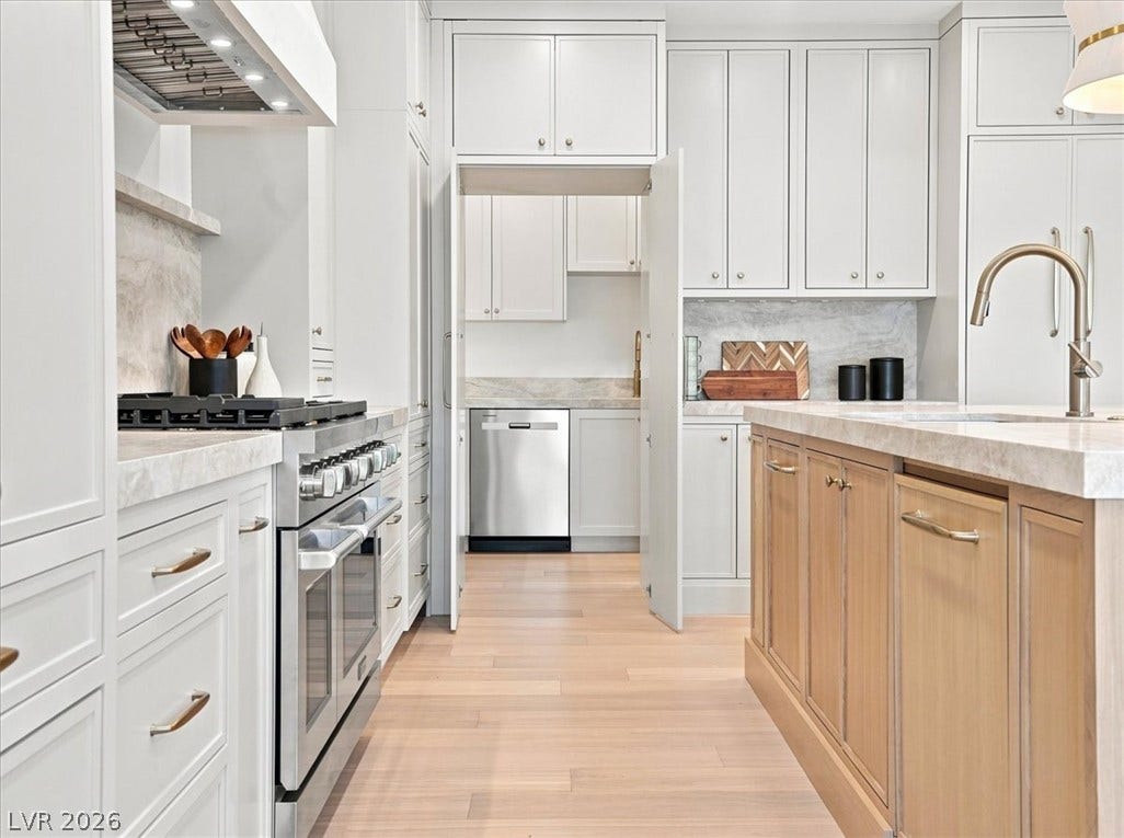 Hardwood floors and stone countertops anchor this modern culinary space with an adjacent prep pantry.