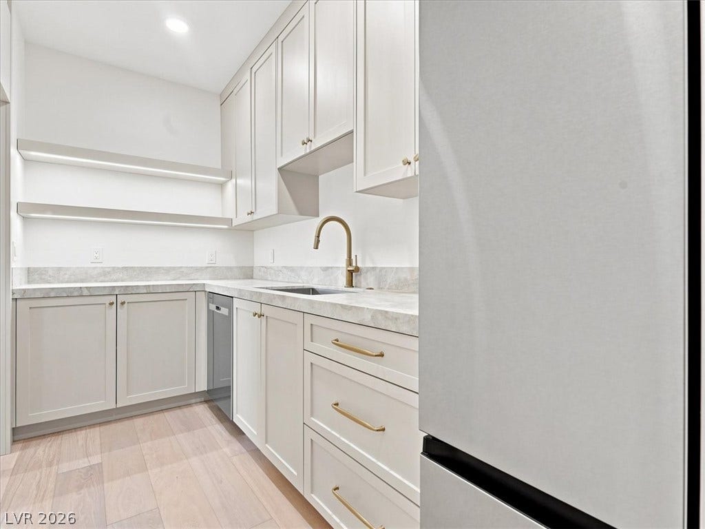 Sleek modern cabinetry, stone countertops, and warm wood flooring define this elegant scullery space.