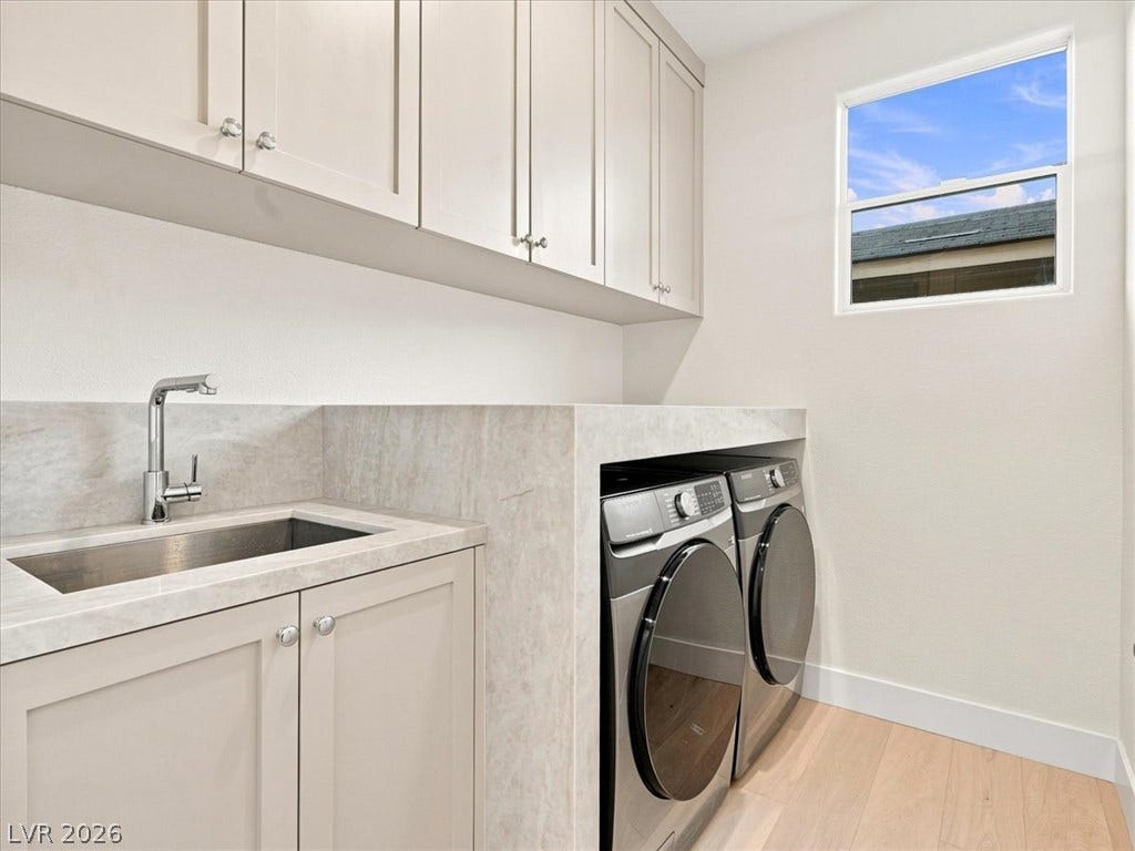 A window brings natural light into this functional laundry space with ample cabinet storage.