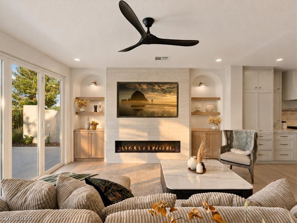 A modern fireplace is flanked by arched built-in shelving in this open living area.