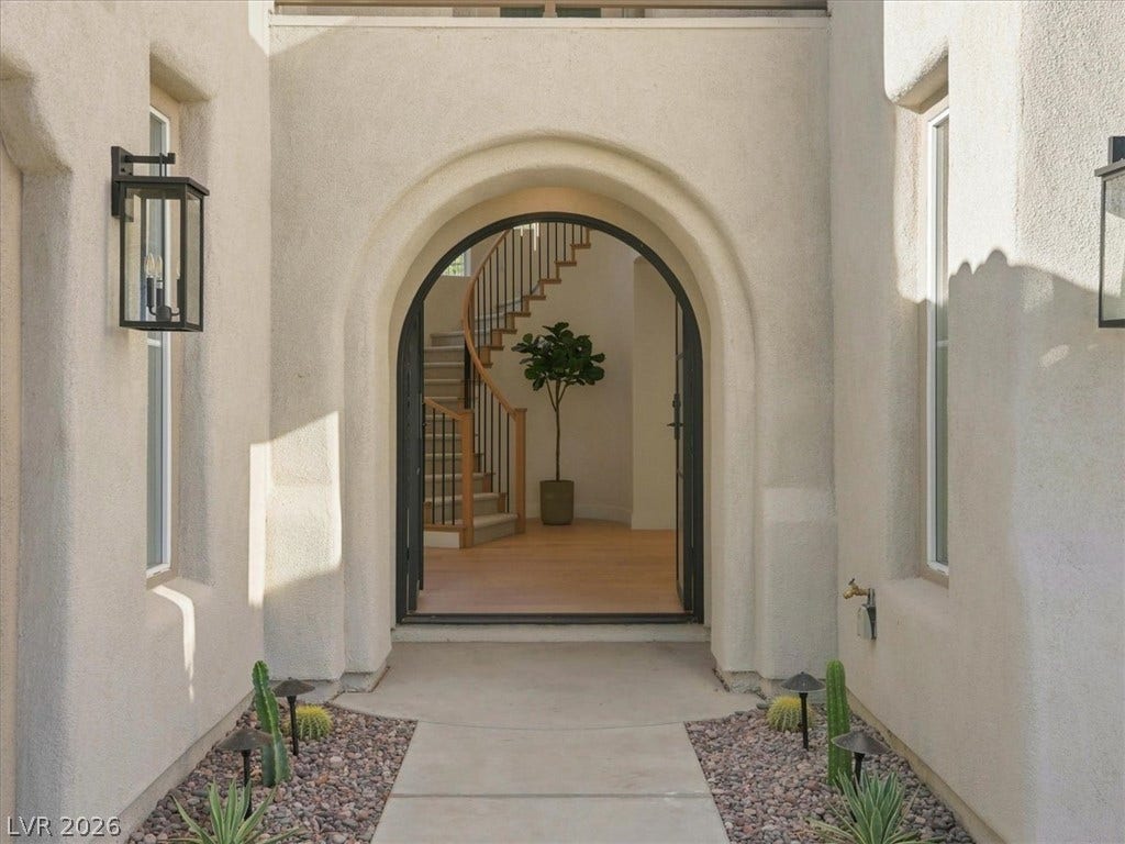 An arched entryway leads into a bright foyer with a sweeping curved staircase.