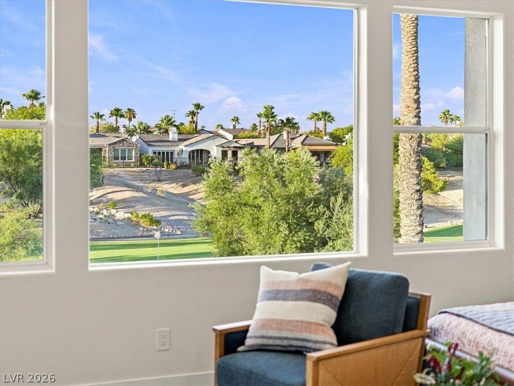 Generous windows frame rolling fairways and mature desert palm trees under bright blue skies.