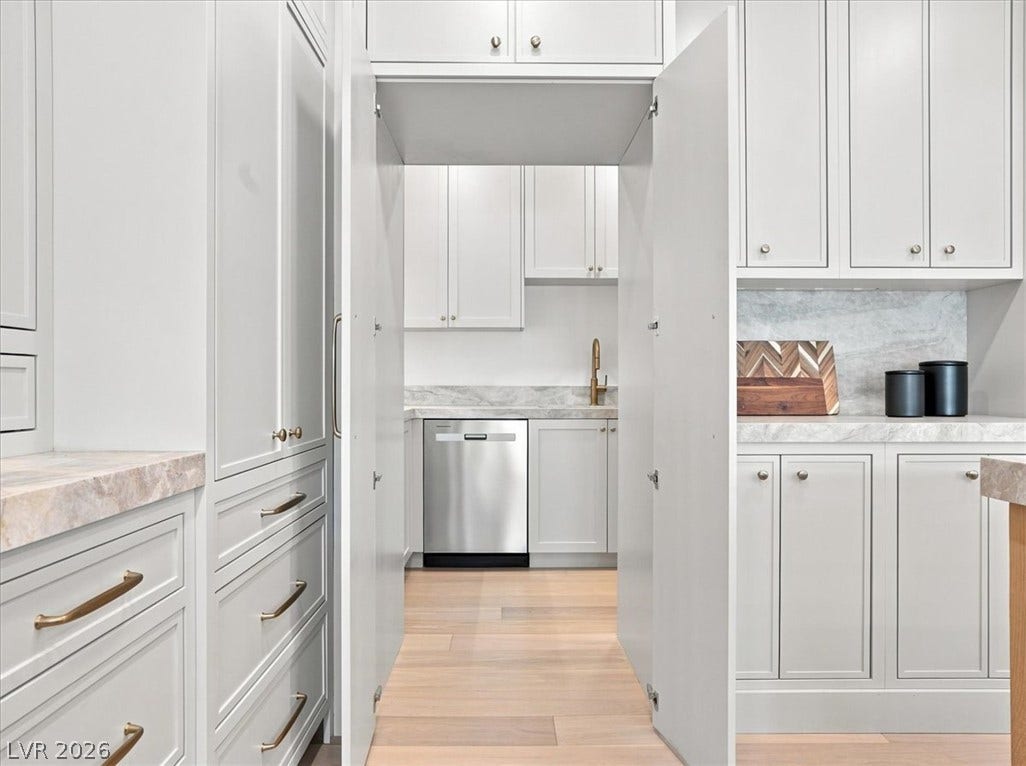 Seamless custom cabinetry opens to reveal a hidden prep kitchen with modern finishes.