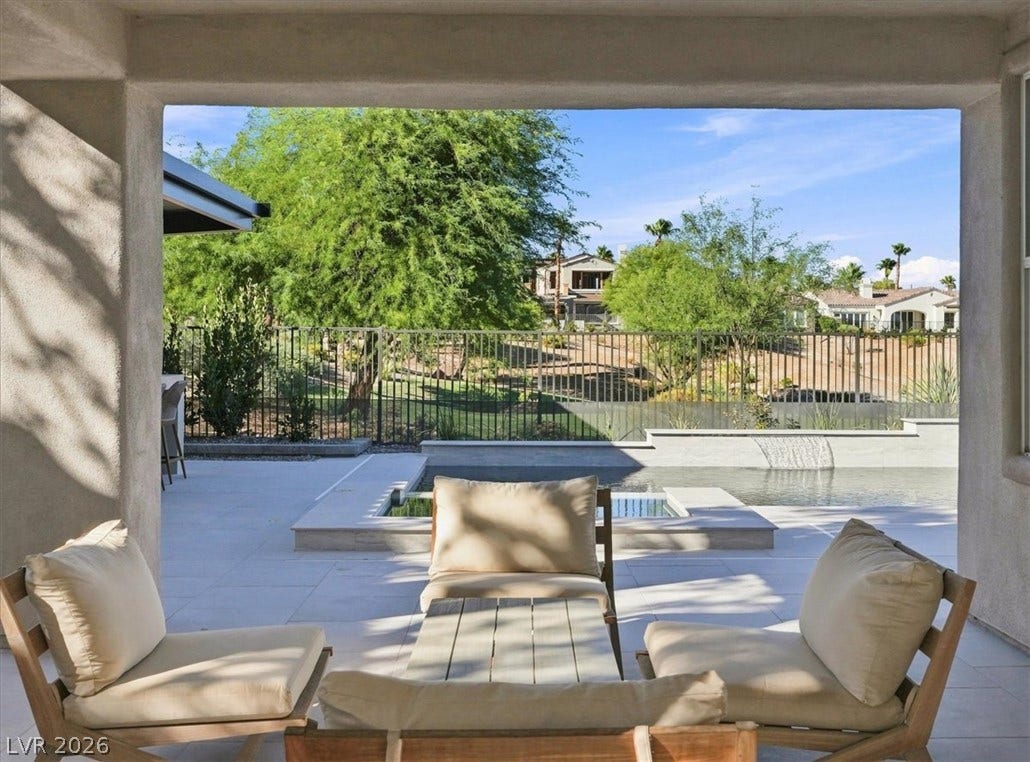 A covered patio overlooks a sparkling pool and manicured landscape.