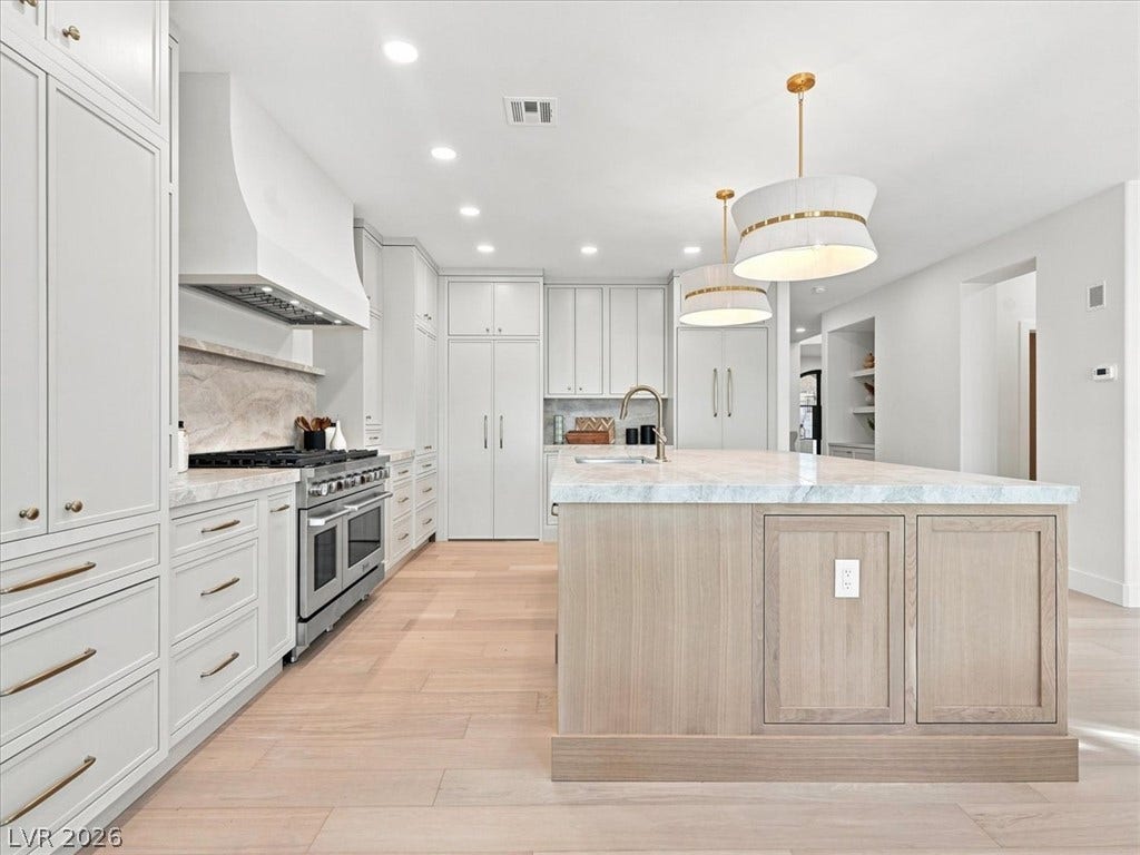 An expansive kitchen features custom cabinetry, premium stone countertops, and warm hardwood flooring.