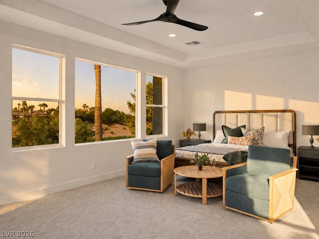 Generous windows frame scenic outdoor views in this bedroom featuring a tray ceiling.