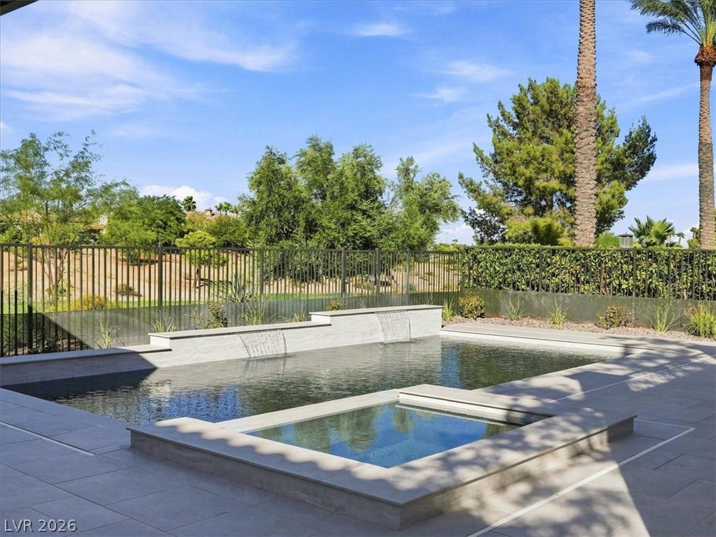An inviting backyard oasis showcases a pristine pool with integrated spa and soothing waterfall features.