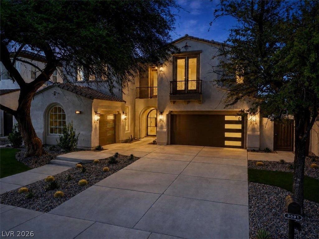 A spacious concrete driveway leads to the elegant multi-level stucco facade and integrated garage.