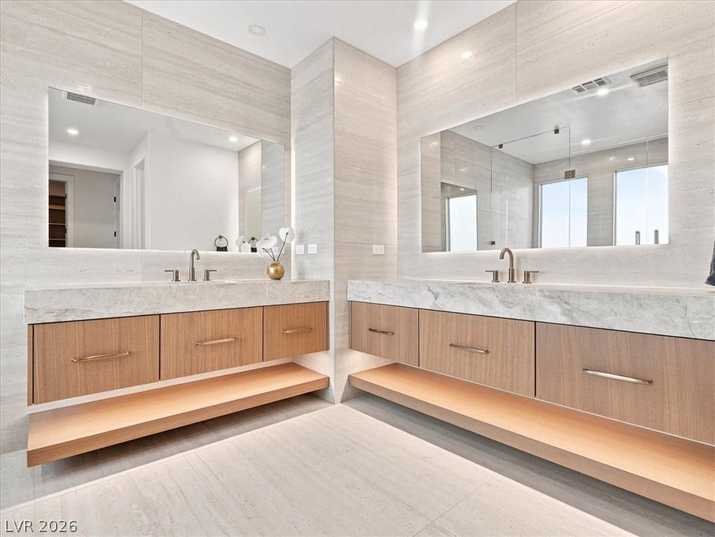 Exquisite stone finishes and custom floating vanities define this modern primary bath retreat.