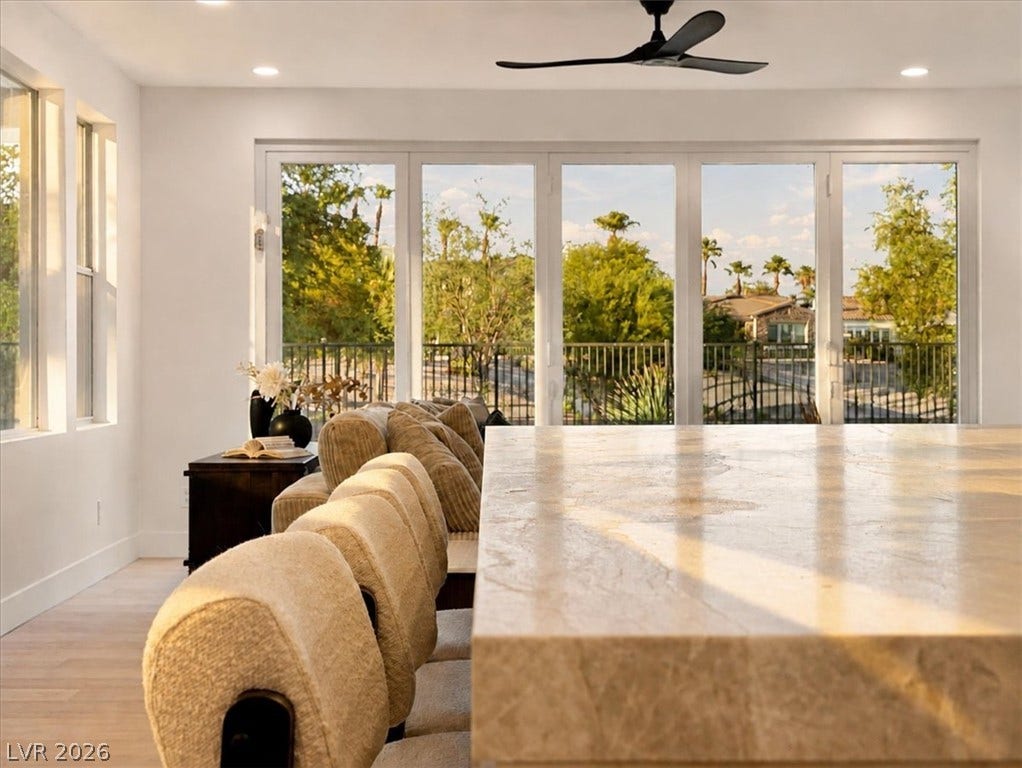 Sunlight streams across a polished stone counter toward a wall of glass doors.