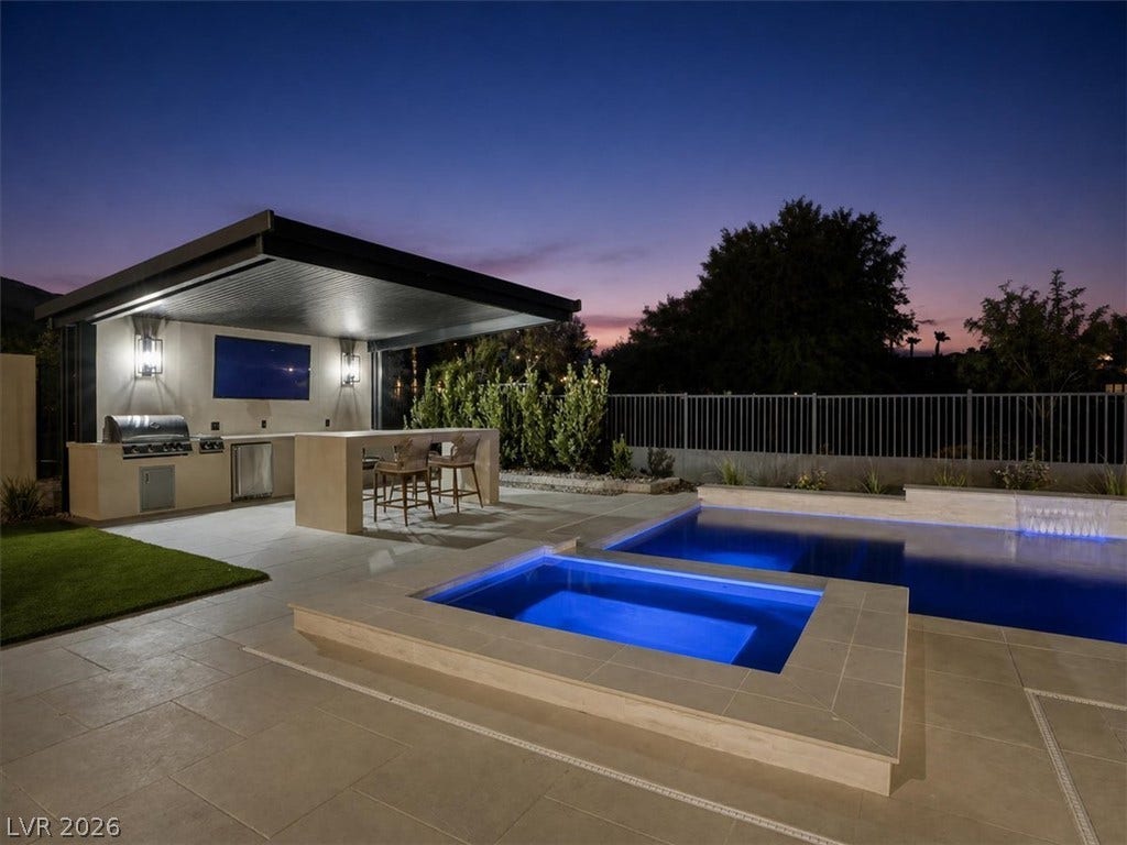 An inviting outdoor kitchen and illuminated pool area provide the perfect setting for twilight entertaining.