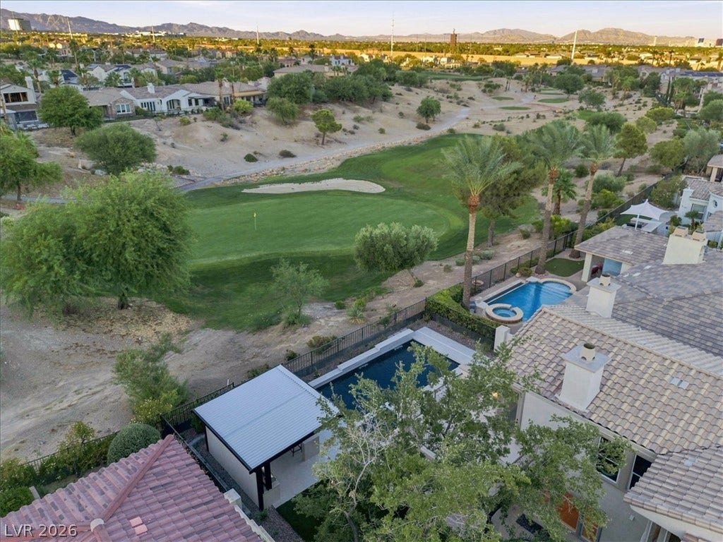 An elevated perspective showcases backyard swimming pools bordering a manicured green golf course.