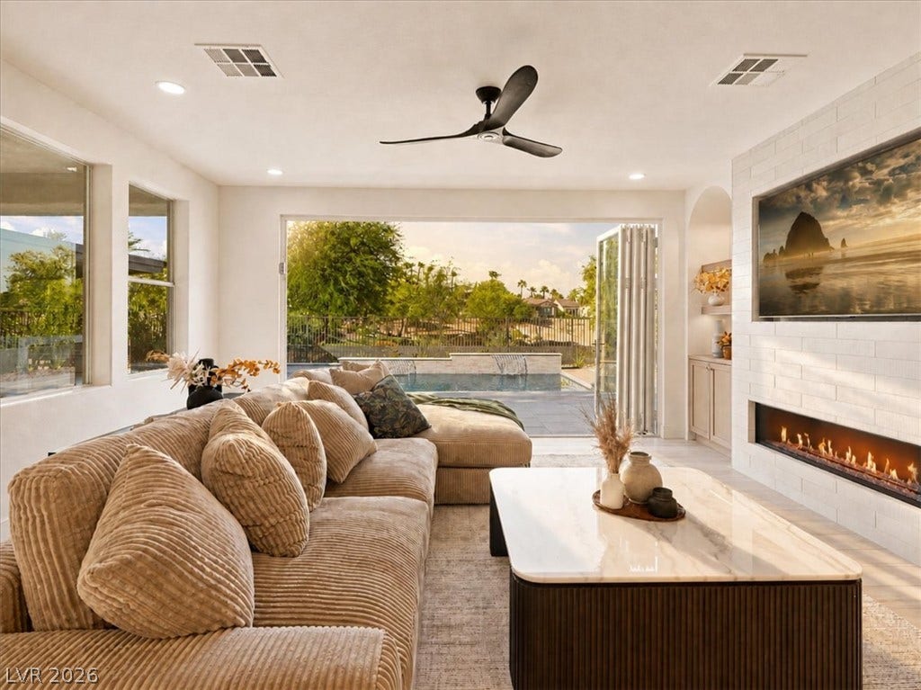 A modern fireplace highlights this seamless indoor-outdoor living area opening to the pool.