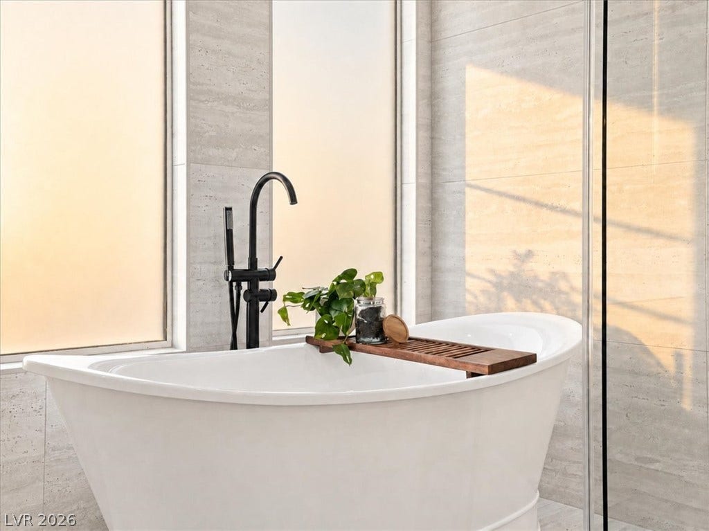A deep soaking tub sits before frosted windows in a tiled alcove.