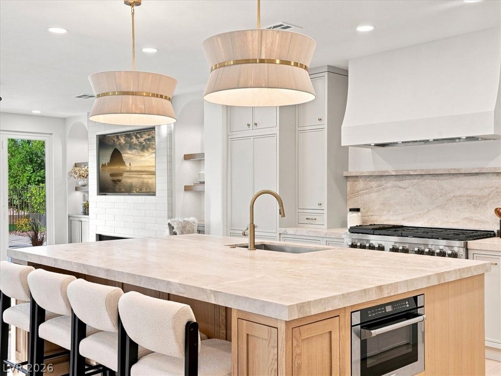 Gleaming stone countertops and a spacious island anchor this light-filled modern kitchen.