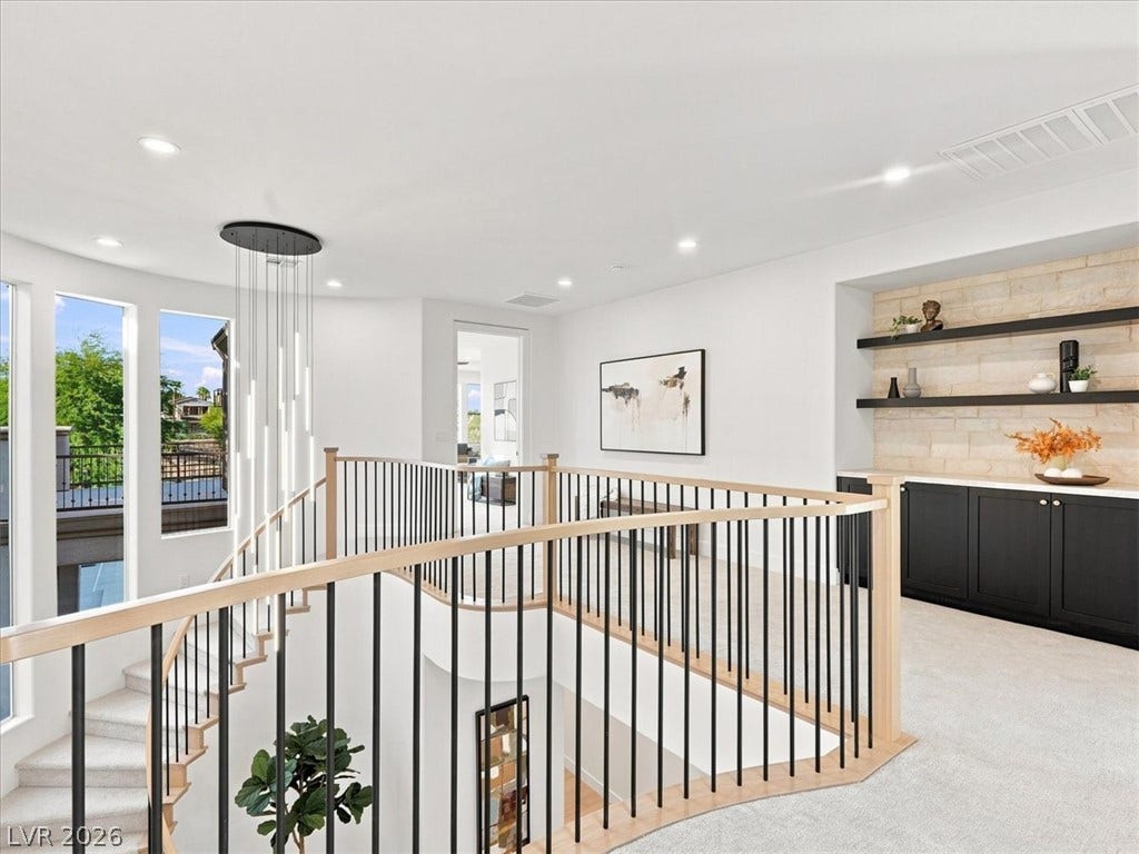 An open upper landing connects a staircase with a built-in wet bar alcove.
