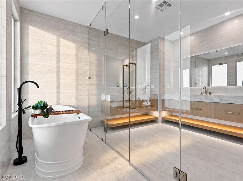 Floor-to-ceiling tiling and a freestanding soaking tub create a luxurious modern bath experience.