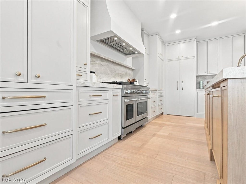 Gleaming hardwood floors and custom cabinetry anchor this culinary space with a professional range.