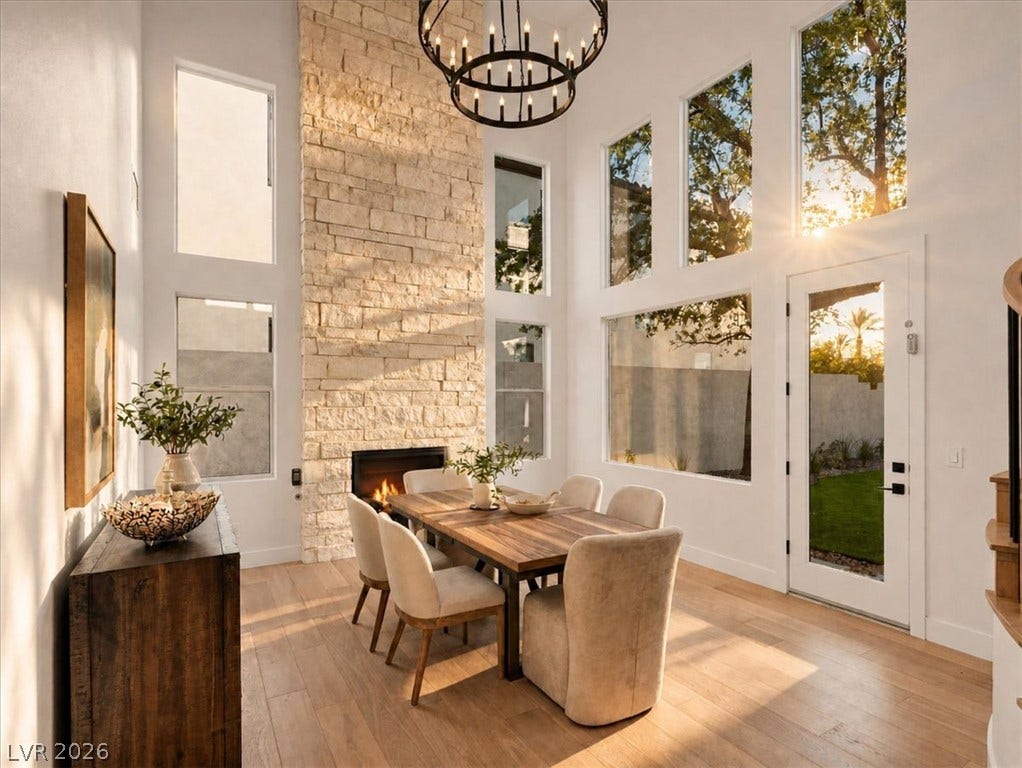 Double-height ceilings and a floor-to-ceiling stone fireplace anchor this airy dining space.