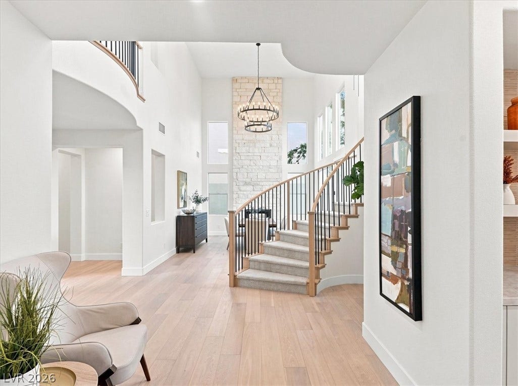 An elegant curved staircase anchors this bright entryway featuring polished hardwood flooring and towering ceilings.