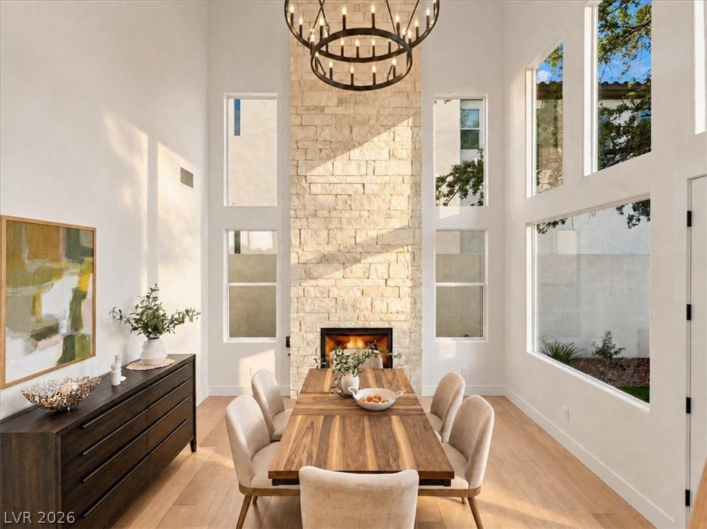 Towering ceilings and a floor-to-ceiling stone fireplace frame this dramatic dining space.